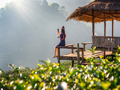 woman-wearing-hill-tribe-dress-sitting-hut-green-tea-field